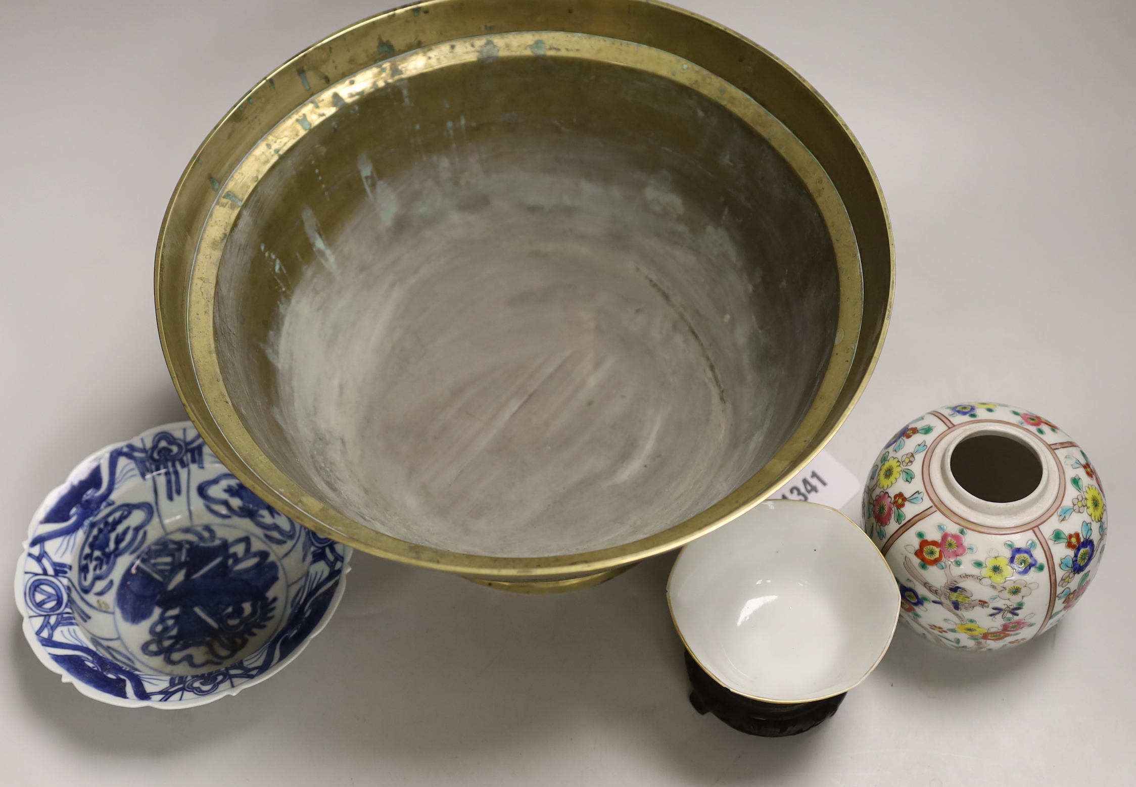 An early 20th century Chinese famille rose tea bowl and stand together with a brass ‘dragon’ bowl, a blue and white bowl and a jar